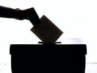 Silhouette af hånd der kommer stemmeseddel i en kasse