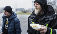 Hjemlæse ældre mand med tallerken i hånden på gaden ved madudlevering